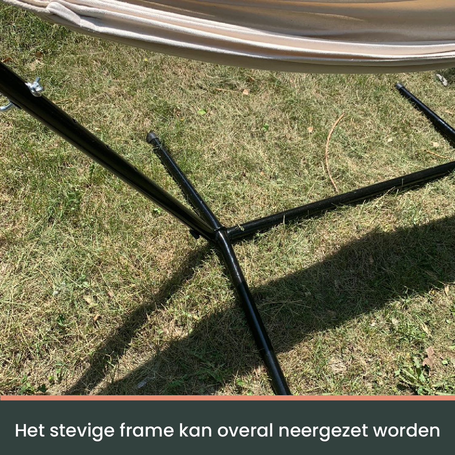 Een crèmekleurige hangmat met witte kabels hangt op een zwarte metalen standaard, ideaal voor ontspanning in de tuin of op het terras.