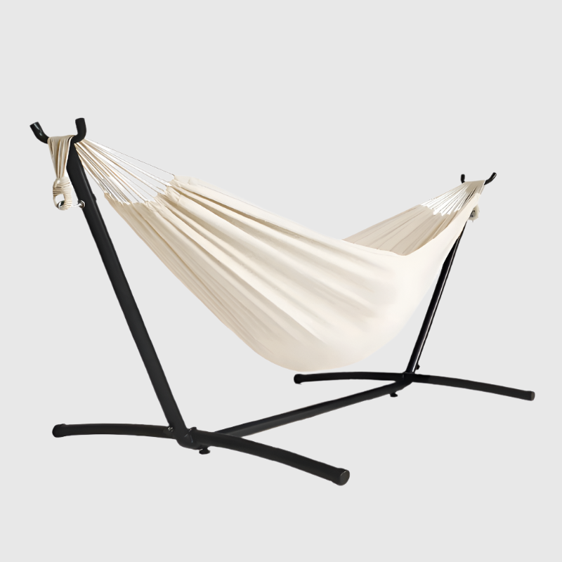 Een crèmekleurige hangmat met witte kabels hangt op een zwarte metalen standaard, ideaal voor ontspanning in de tuin of op het terras.