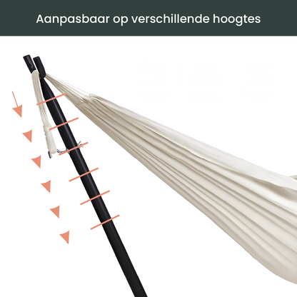 Een crèmekleurige hangmat met witte kabels hangt op een zwarte metalen standaard, ideaal voor ontspanning in de tuin of op het terras.