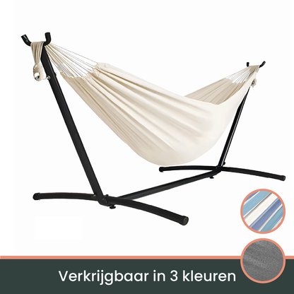 Een crèmekleurige hangmat met witte kabels hangt op een zwarte metalen standaard, ideaal voor ontspanning in de tuin of op het terras.