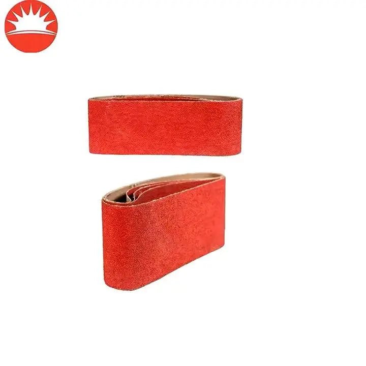 Rode sandpapierbanden met zichtbare korrelstructuur, geschikt voor het schuren van metaal en hout. De banden tonen een heldere kleur en zijn voorzien van een bruine onderlaag.