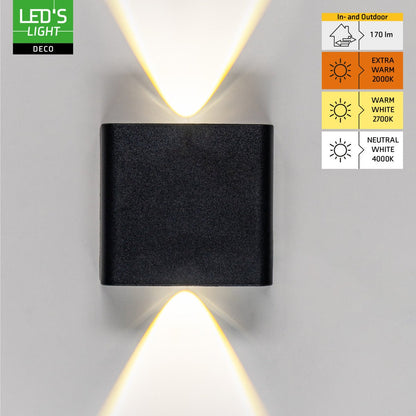 Zwart wandlamp met warm wit licht, geïnstalleerd op een grijze muur boven een bruine bank. Geschikt voor buitenverlichting en avondelijke sfeercreatie.