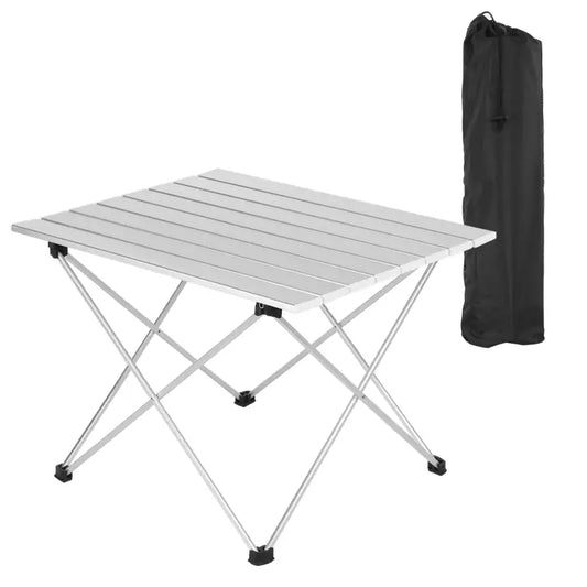 Zilverkleurige vouwtafel met aluminium frame en houten planken, voorzien van zwarte voetbeschermers. Naast de tafel staat een zwarte opbergzak voor kampeer- en reisgebruik.