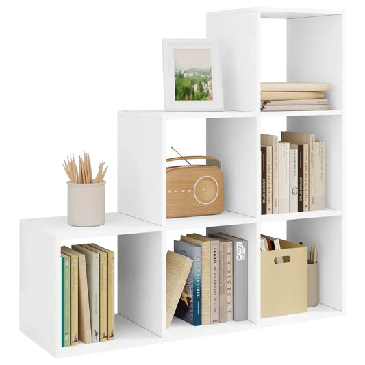 Wit, modulair boekenkastje met verschillende vakken, gevuld met boeken, een houten radio, een fotolijst en een pot met potloden. Ideaal voor een moderne woonkamer of kantoorruimte.