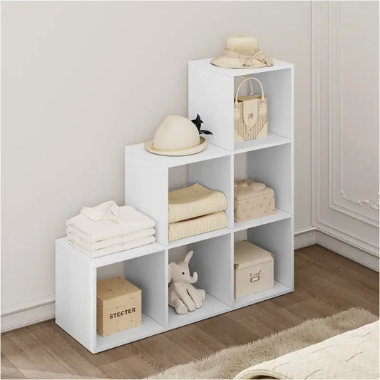 Wit, modulair boekenkastje met open vakken, gevuld met boeken, een houten radio en een fotolijst. Ideaal voor moderne woonkamer- of kantoordecoratie met minimalistische stijl.