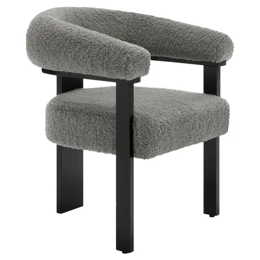 Grijze, fluweelachtige fauteuil met zachte, gebogen armleuningen en een comfortabele zitting, ondersteund door zwarte metalen poten. Ideaal voor moderne woonkamer of lounge-ruimte.