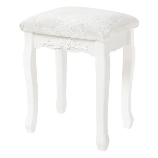 Een witte, klassieke houten kruk met gedetailleerde bloemversiering en een zacht, geborduurd zitvlak. Perfect voor een elegante make-up of schoenenopbergplek in een slaapkamer.