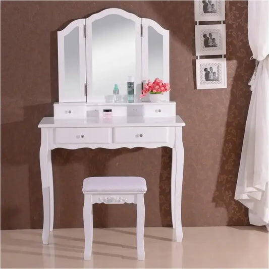 Een witte, klassieke make-up tafel met drievoudig spiegel en meerdere laden, geleverd met een passend witte houten stoel, ideaal voor een elegante slaapkamer of make-up ruimte.