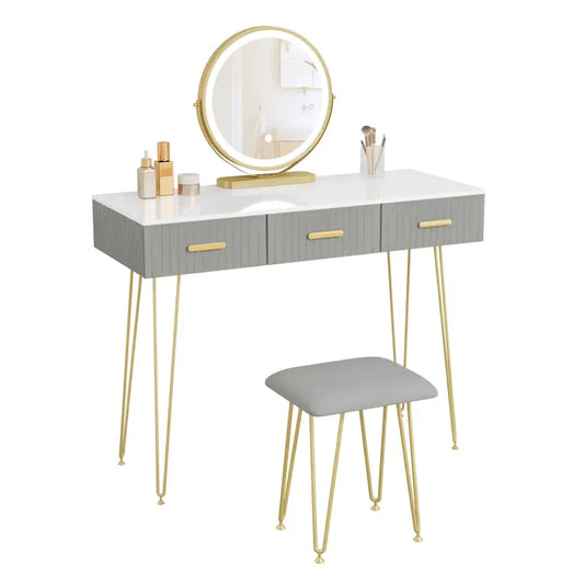 Een moderne make-up tafel met witte blad, grijze lades en gouden metalen poten, voorzien van een ronde, verlichte spiegel. Geïnspireerd op de jaren '50, ideaal voor een stijlvolle make-up of sieradenruimte.