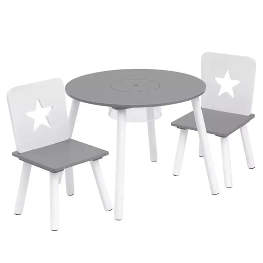 Grijs houten kindertafelset met twee stoelen, witte poten en sterren op de rugleuningen. Tafel heeft opbergvak en speelgoed zoals een teddybeer en blokken. Ideaal voor speelruimte of creatieve activiteiten.