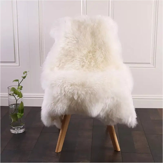 Een zachte, witte schapenbont deken ligt op een houten stoel, perfect voor een warme zitplek. Ideaal als decoratief element in een moderne woonkamer of slaapkamer.