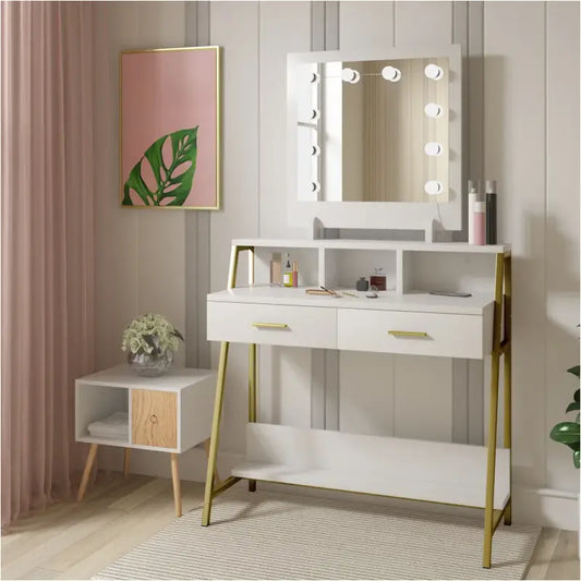 Een witte make-up tafel met goudkleurige metalen poten en een spiegel met omringende lichtjes. Het meubel heeft twee laden met gouden handgrepen en een onderste plank, ideaal voor make-up opslag.