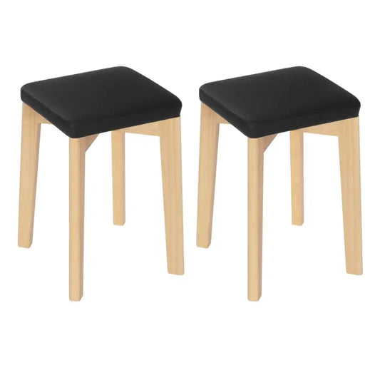 Zwarte, gepolsterde houten krukken met lichtgekleurde poten, geschikt voor keuken of badkamer. Eenvoudige, moderne design voor comfortabele zitting in elke woonruimte.