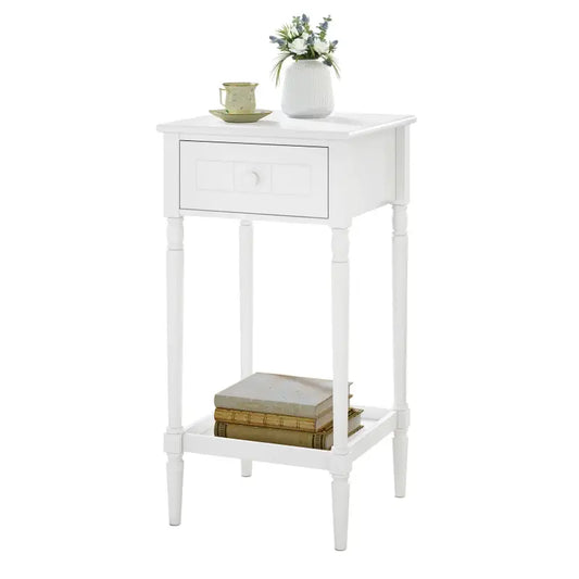 Een witte nachtkastje met één lade en een ondersteunende plank, voorzien van gedraaide poten en een witte knop. Ideaal als bijzettafel voor slaapkamer of woonkamer.
