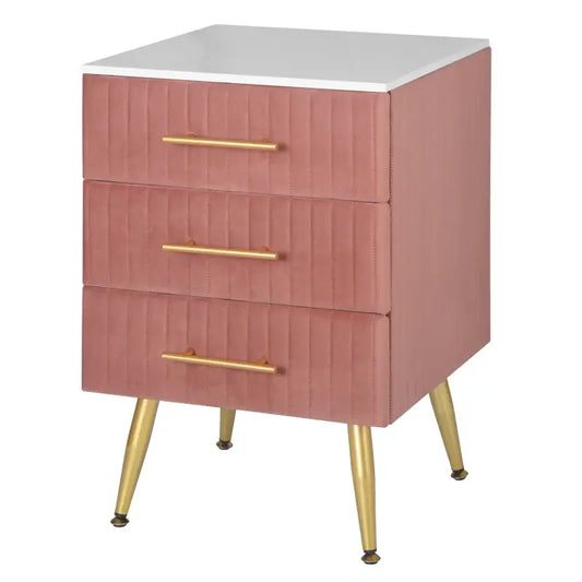 Een roze, gestoffeerde nachtkastje met drie laden en goudkleurige handgrepen, voorzien van elegante, goudkleurige poten. Geschikt als slaapkamermeubel of bij een modern interieur.
