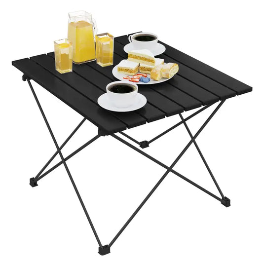 Zwarte vouwtafel met houten planken, geschikt voor koffie of picknick. Met glazen, koffiekopjes en gebak op een zonnige dag.