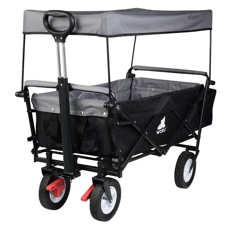 Zwarte vouwbare kinderwagen met grijze stoffen dak en zitplaats, voorzien van vier rubberen wielen met rode remmen. Ideaal voor wandelingen en kamperen in de natuur.