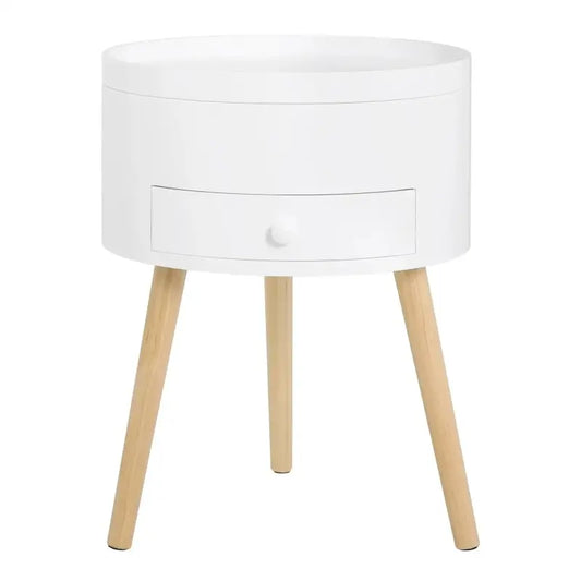 Een witte, ronde nachtkastje met een enkel ladevak en een witte knop, ondersteund door drie lichte houten poten, geschikt als slaapkamermeubel of bij een bed.