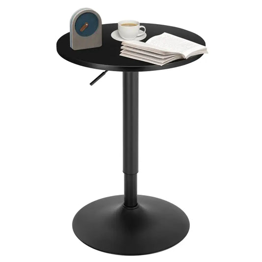 Een zwarte, ronde verhoogbare tafel met een stijlvolle metalen potenstructuur, geschikt voor kantoor- of woonruimte. Op de tafel staat een koffiekopje, een open boek en een vintage wekker.
