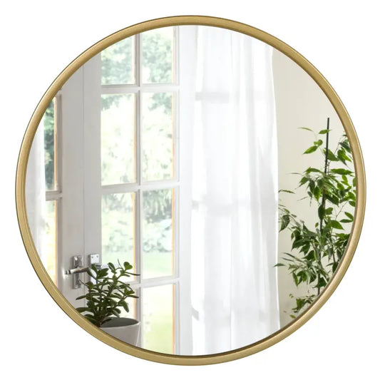 Rond spiegel met goudkleurige metalen lijst, weerspiegelt een zonnige kamer met witte gordijnen en groene planten. Perfect voor woonkamer of slaapkamerdecoratie.