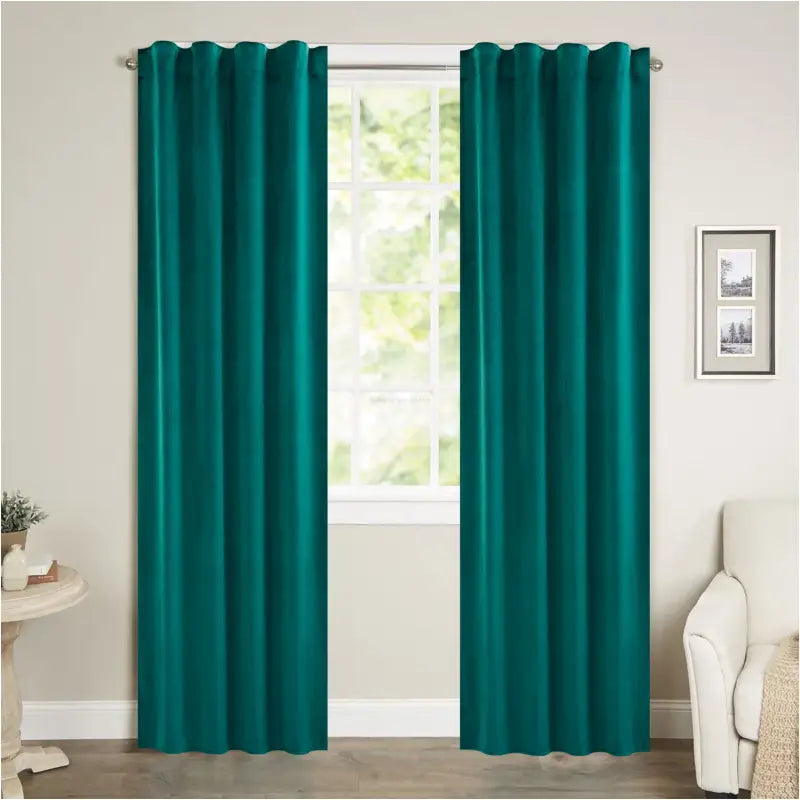 Turquoise gordijnen met grommetten hangen elegant voor een raam in een woonkamer, gemaakt van zacht, glanzend materiaal. Perfect voor privacy en stijl in moderne interieurs.