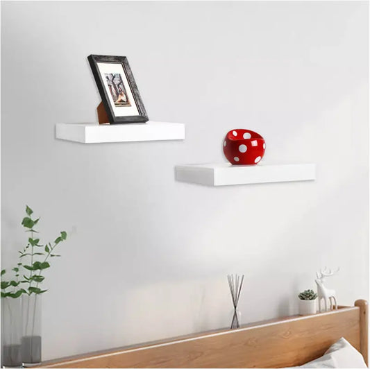 Witte wandplanken met minimalistisch ontwerp, voorzien van een zwart fotolijstje en een rode stippenbowl. Perfect voor moderne slaapkamerdecoratie en ruimtebesparende opberging.