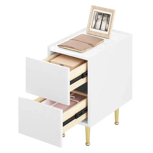 Een witte, minimalistische nachtkastje met twee laden en goudkleurige poten, geschikt voor moderne slaapkamers. Perfect voor opbergen van nachtkastjeaccessoires en slaapkamerdecoratie.