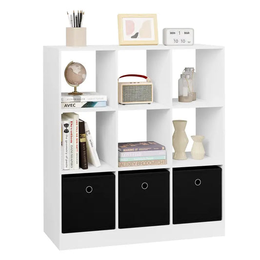 Een witte kubusboekenkast met zwarte opbergvakken, gevuld met boeken, een wereldbol, een vintage radio en decoratieve accessoires, ideaal voor een moderne woonkamer of kantoorruimte.