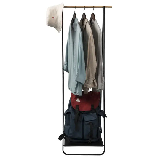 Een minimalistisch zwart metalen kledingrek met houten hangers, beladen met lichtblauwe en beige overhemden en een roze hoed. Onderaan rust een rode en blauwe rugtas, ideaal voor kleine ruimtes en kledingopslag.