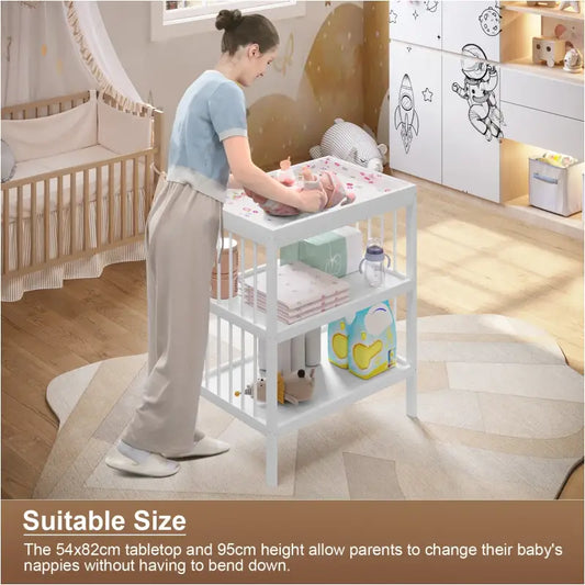 Een wit houten babyverzorgingskastje met drie planken, voorzien van een bloemenprint deksel en gevuld met luiers, flesjes en verpakkingen. Ideaal voor babyverzorging en kinderkameropslag.