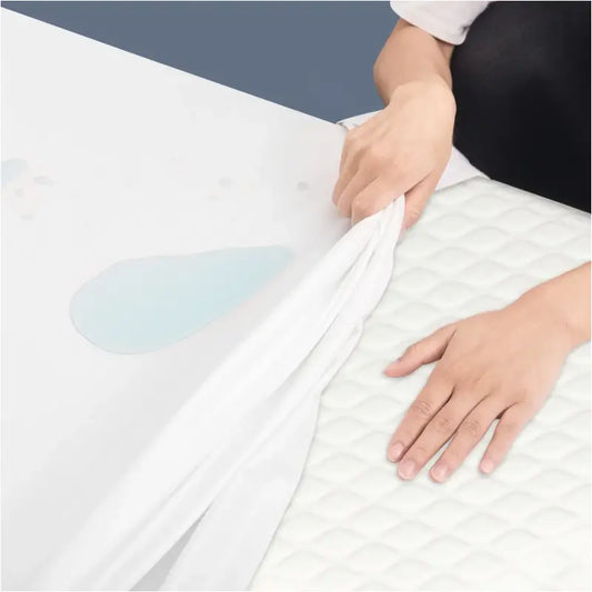 Een witte, waterafstotende matraslaken wordt getest op een gestikt wit matras, waarbij een blauwe vlek zichtbaar blijft. Perfect voor kinderen en allergieklachten, met een zachte, beschermende textuur.