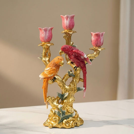 Gouden kandelaar met twee kleurrijke papegaaien en roze tulpen, geschikt als decoratie voor woonkamer of tafel. Prachtige detailwerk en glanzende finish voor een luxe interieur.
