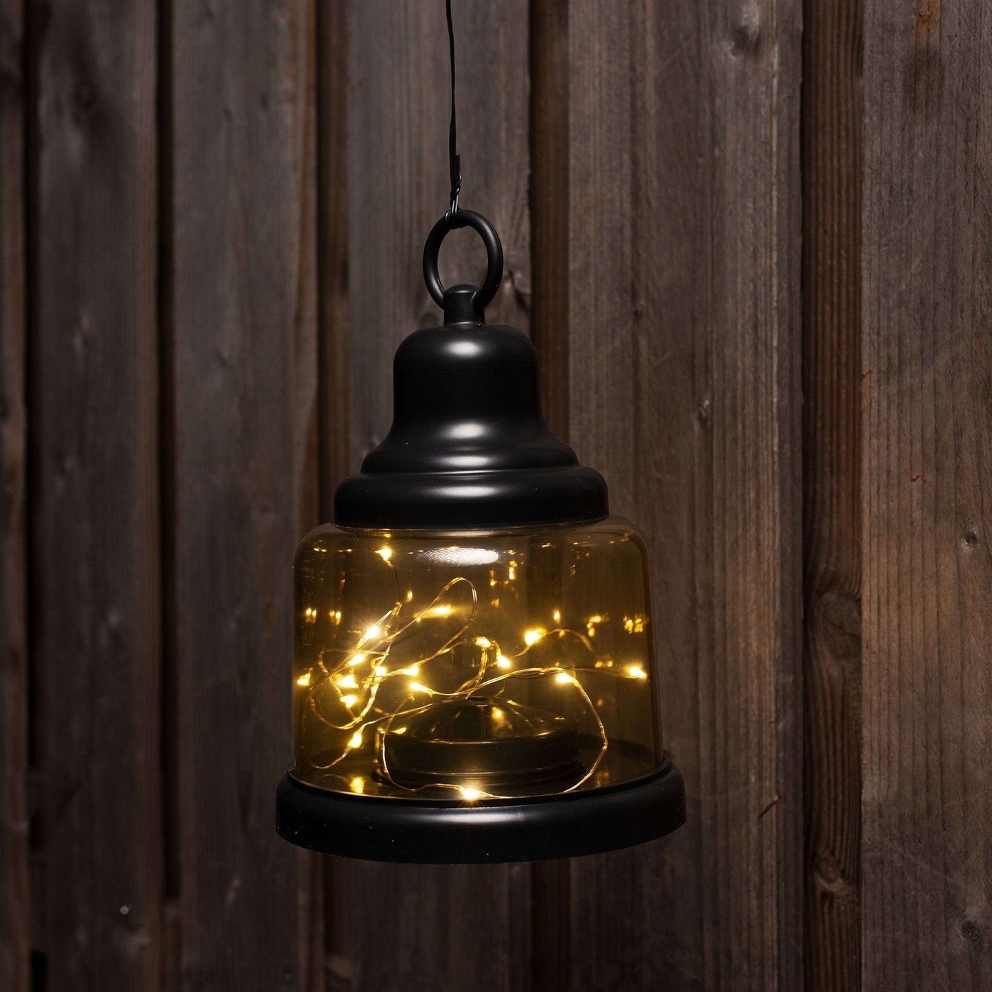 Een zwarte, glazen hanglamp met warme LED-verlichting, geschikt voor sfeerverlichting in woonruimtes. De lamp heeft een handige ring voor ophangen en een zichtbare LED-kring binnenin.
