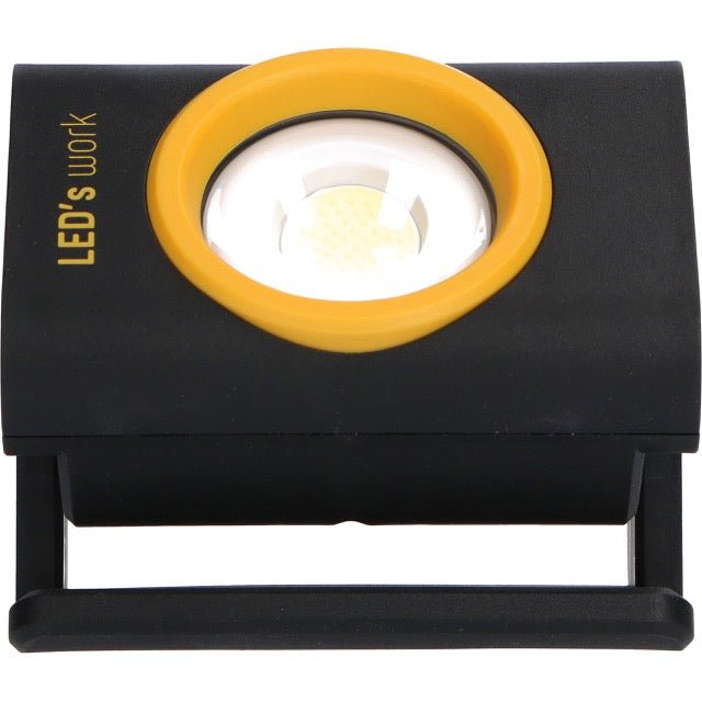 Zwart LED-lampje met geel kader en magnetische aansluiting, voorzien van een witte reflector en het opschrift 'LED's work'. Ideaal voor werktuigengebruik en reparaties in donkere ruimtes.