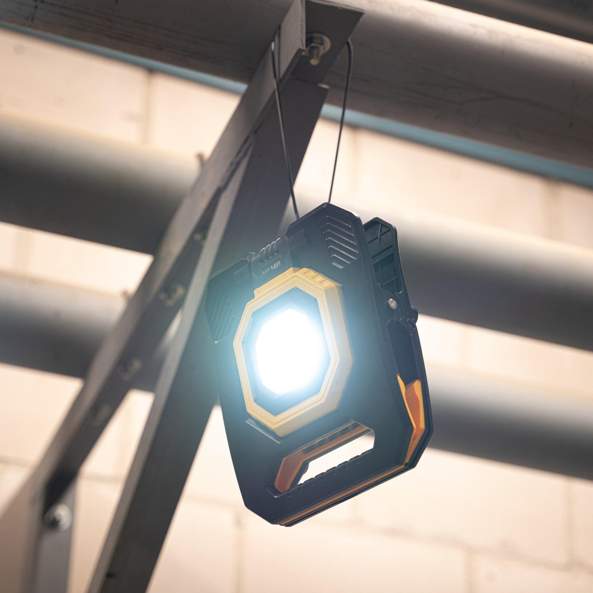 Een robuuste, zwart-gele LED werklamp met handvat en zichtbare LED’s, geschikt voor professioneel gebruik. Geschikt voor werken in donkere ruimtes of als noodverlichting.