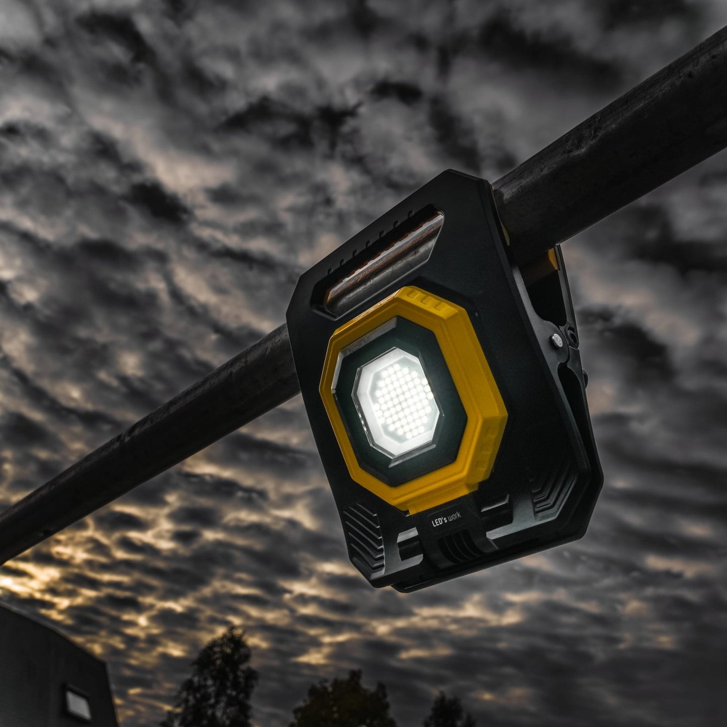 Een robuuste, zwart-gele LED werklamp met handvat en zichtbare LED’s, geschikt voor bouw- en onderhoudsprojecten. Compacte, waterdichte constructie met grip-oppervlakken voor betrouwbare gebruik.
