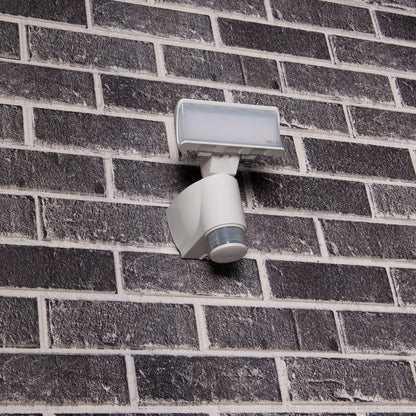 Een witte bewegingssensorlamp met transparante kap, geschikt voor buitenverlichting. Het apparaat detecteert beweging en is ideaal voor veilige verlichting van tuinen en gangpaden.