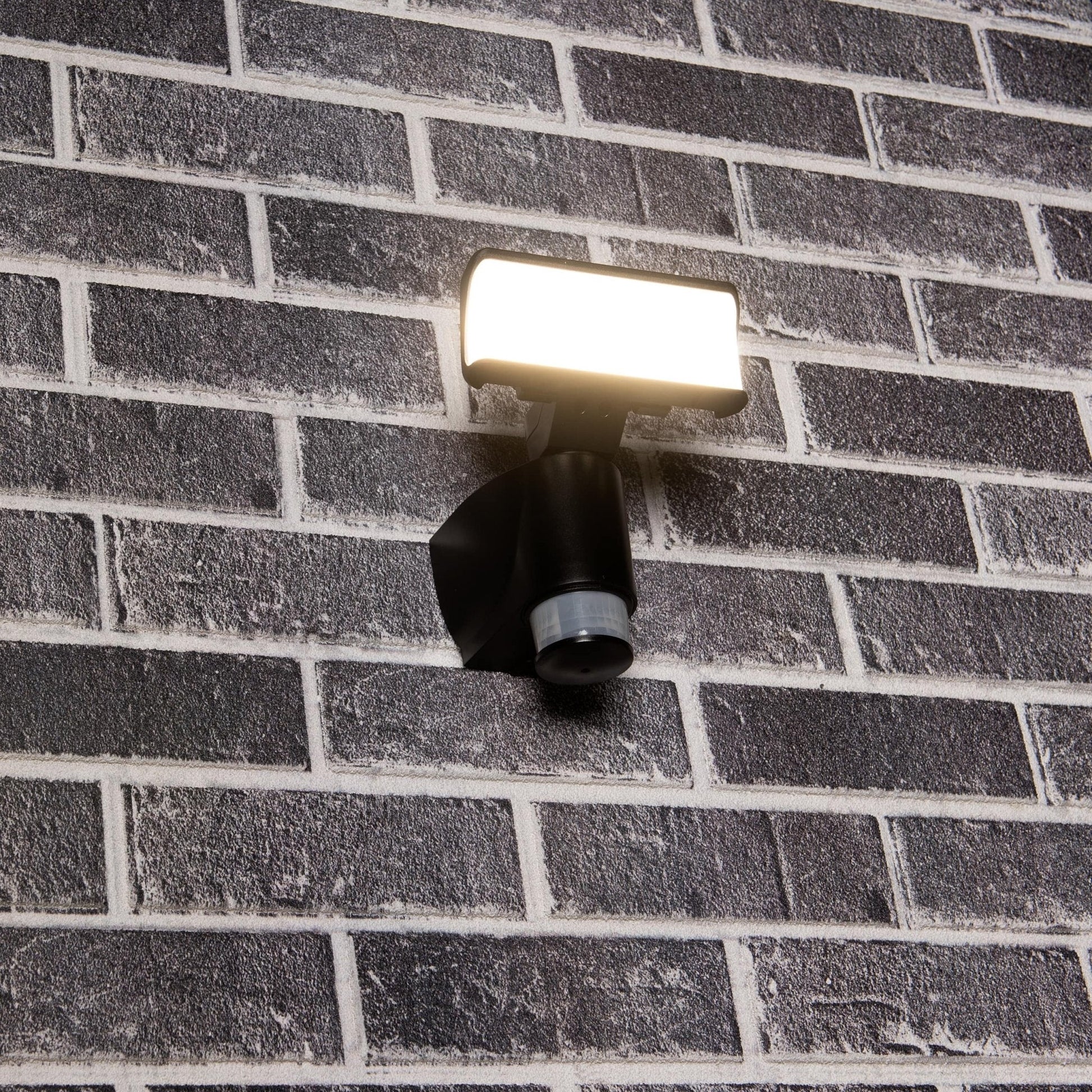Zwarte bewegingssensorlamp met helder witte LED-verlichting en infrarood sensoren, geschikt voor veilige verlichting van tuinen en buitenruimtes. Automatisch inschakelen bij beweging voor nachtverlichting.