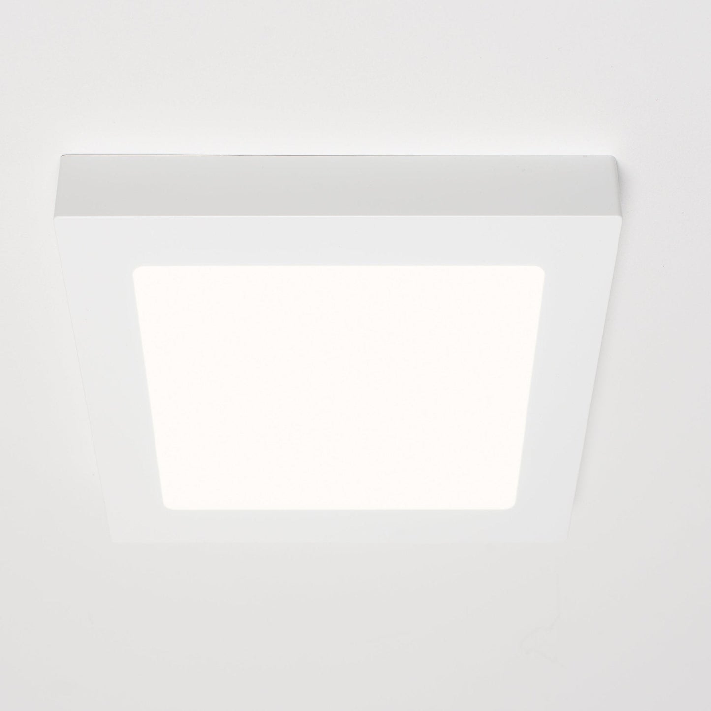Een witte, vierkante LED-downlight met zichtbare afwerking, geplaatst naast zijn verpakking. Geschikt voor zowel ingebouwde als oppervlakkige installatie in moderne interieurs.