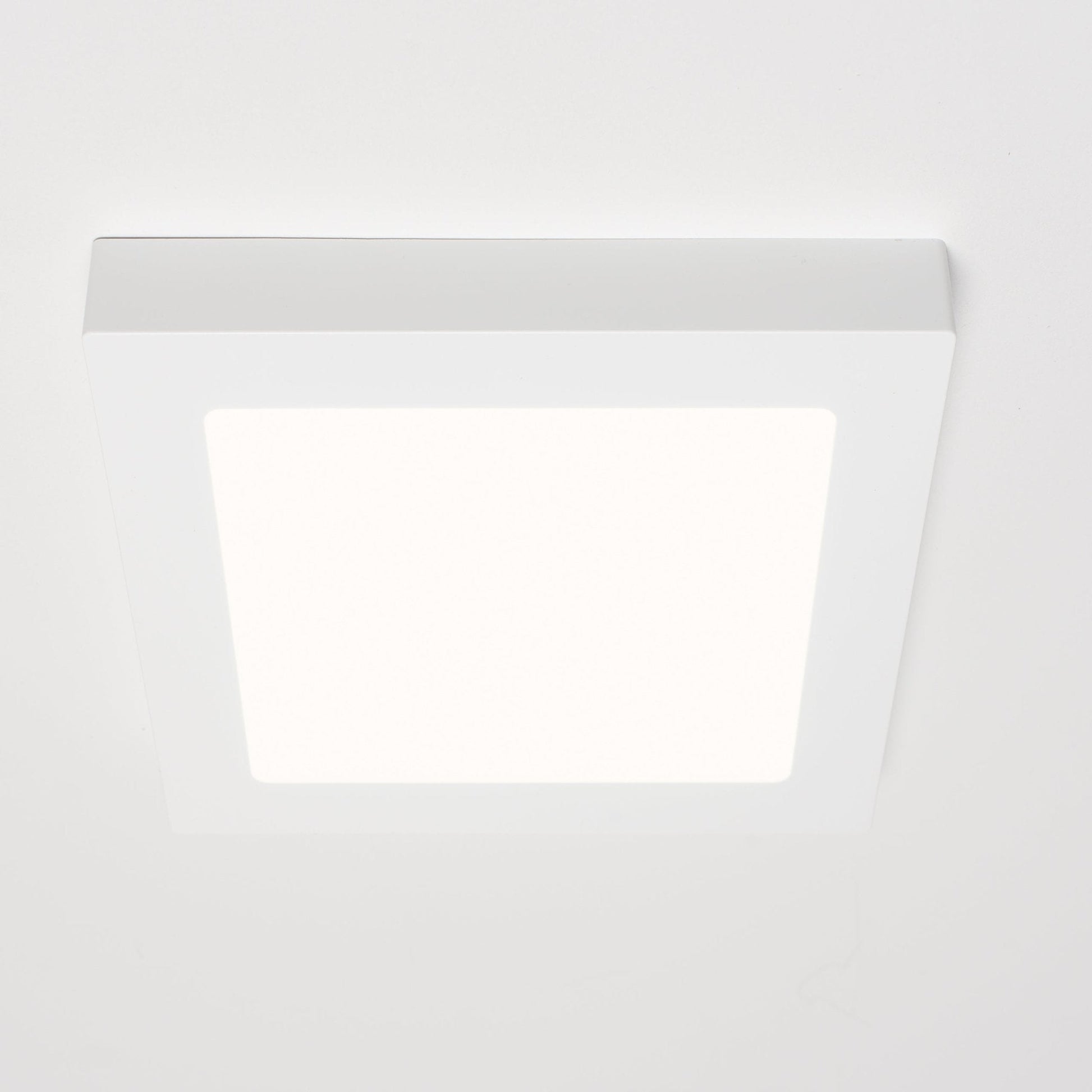 Een witte, vierkante LED-downlight met zichtbare afwerking, geplaatst naast zijn verpakking. Geschikt voor zowel ingebouwde als oppervlakkige installatie in moderne interieurs.