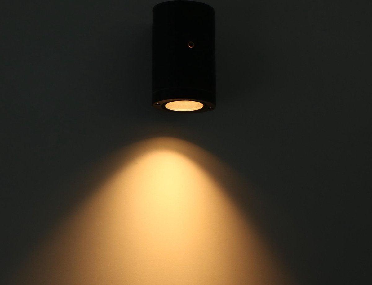 Zwart cilindrische wandlamp met goudkleurige rand en warm wit licht, geschikt voor moderne interieurs. Compacte design voor wandmontage in woon- of werkomgevingen.