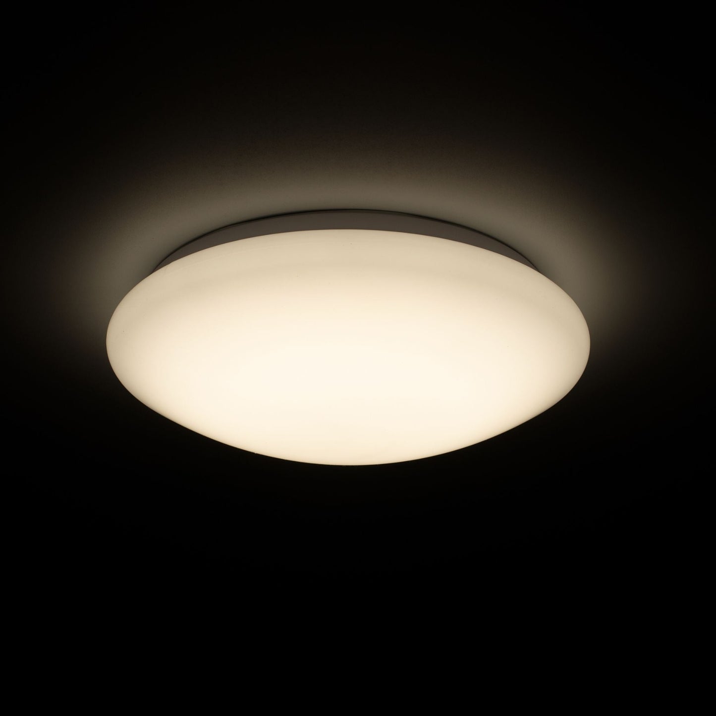 Een witte, ronde plafondlamp met een gladde, mat witte kap en een zichtbare zilverkleurige rand. Geschikt voor moderne interieurs en als energiezuinige verlichting in woon- en werkkamers.