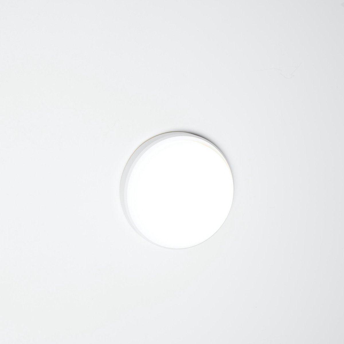 Een witte, ronde plafondlamp met glad oppervlak en gestreepte rand, geschikt voor moderne interieurs. Ideaal voor woonkamers en slaapkamers waar helder, neutraal licht nodig is.