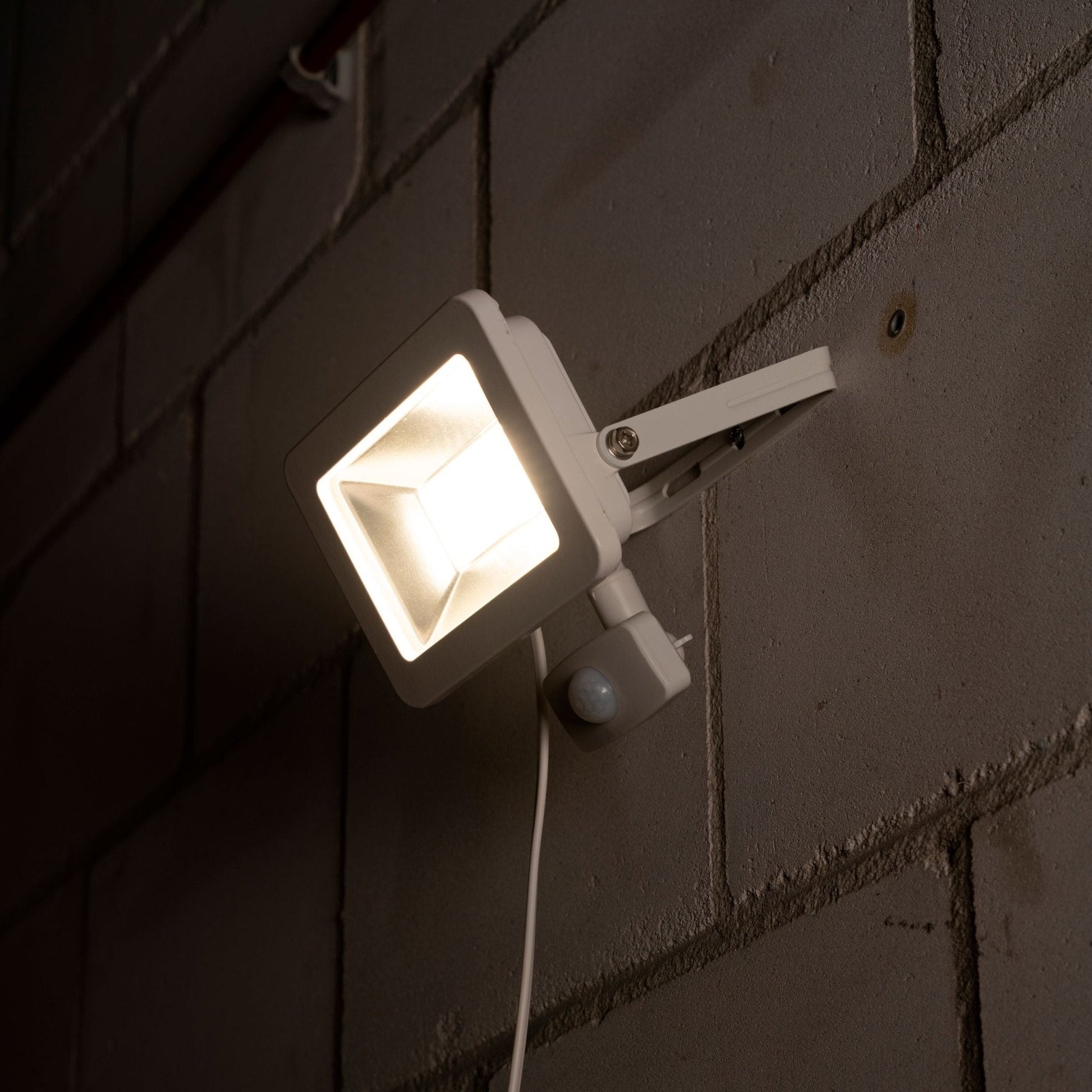 Wit LED-stralingslamp met bewegingssensor, voor buitenverlichting. Zichtbare LED’s en zilverkleurige reflector, geschikt voor tuin- en terrasverlichting.