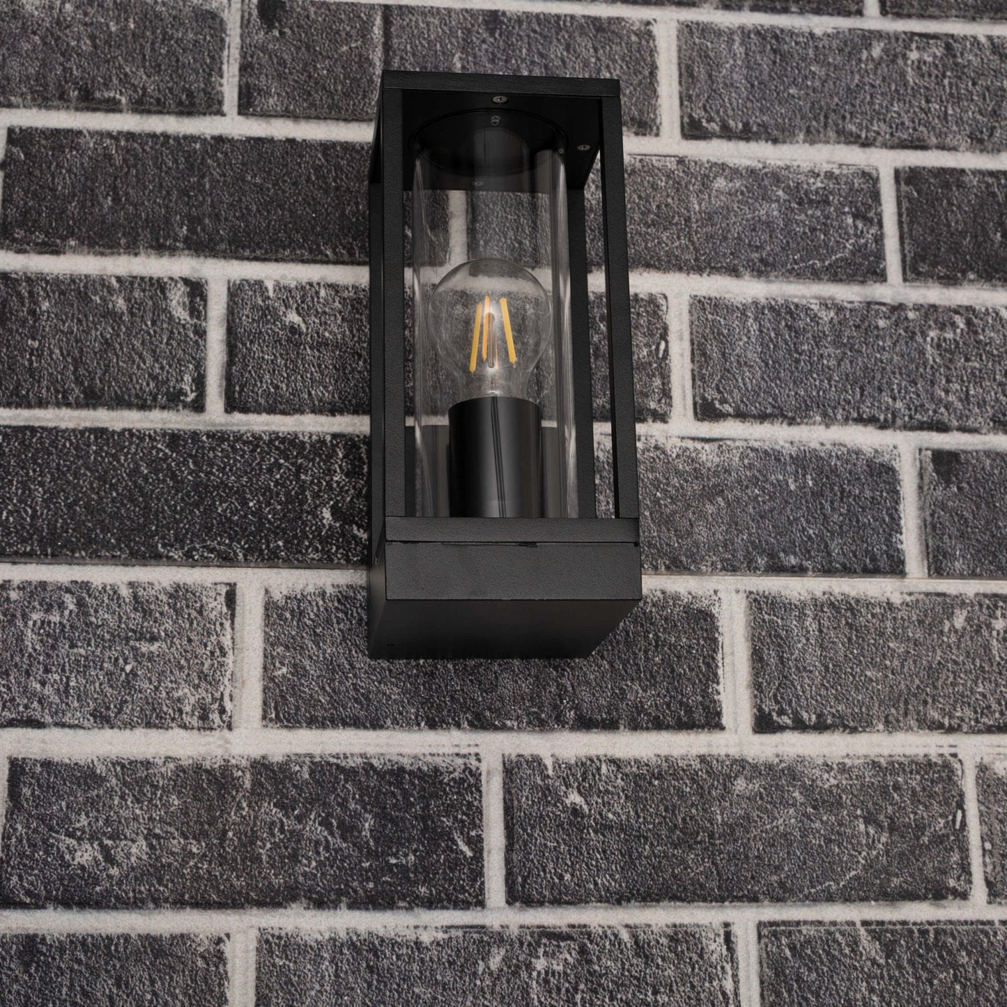 Een zwart, rechthoekig buitenspot met glazen panelen en een gloeiende filamentlamp. Perfect voor warme verlichting op terrassen of in de tuin.