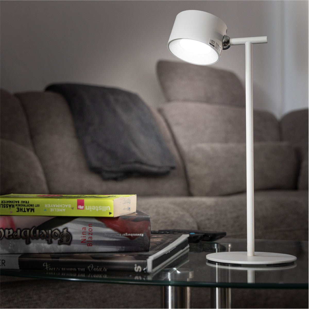 Een witte, opvouwbare LED-tafellamp met draaibare kop en magnetische houder, geschikt voor lezen en werken. Zichtbaar naast de verpakking met productdetails.