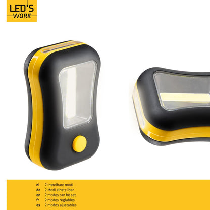 Een compacte, zwarte en gele LED-lamp met een heldere, rechthoekige lichtbron en een opvallende gele knop. Geschikt voor gebruik als noodverlichting of bij werkzaamheden in donkere ruimtes.