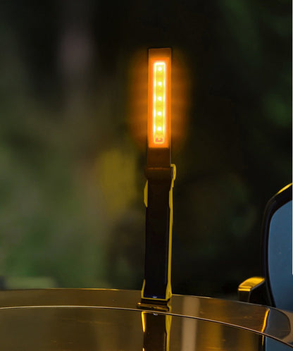 Een gele, opvouwbare LED-werklicht met zwart metaallichaam en zichtbare knoppen, geschikt voor precisiewerkzaamheden. Compacte uitvoering voor gebruik in werkplaatsen of bij reparaties.