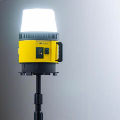 Een gele en zwarte batterijoplaadbare werklamp met witte kap en rode accu-connector, geschikt voor gebruik in bouw- en onderhoudsprojecten.