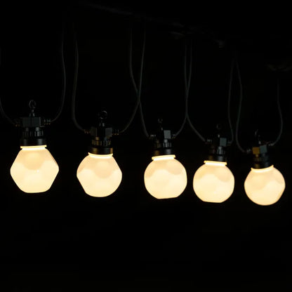 Zes warm witte LED-lampjes hangen aan een zwart kabelsysteem, geschikt voor binnen- en buitenruimtes. De set bevat 10 lampen met een plug voor gemakkelijke installatie.